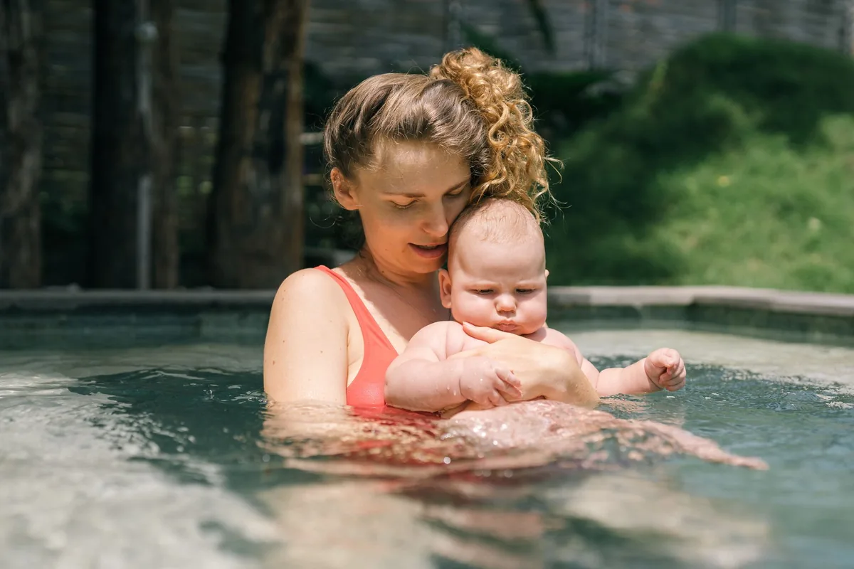 Une mère tient son bébé dans l'eau d'une piscine